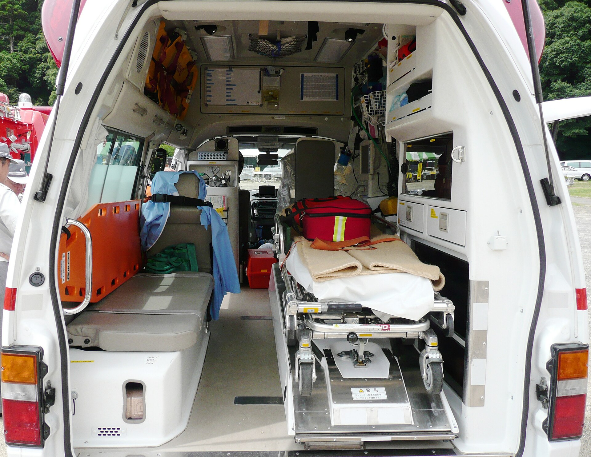 L'arrière d'une ambulance ouvert : le brancard au centre, les sièges et le matériel de soins sur les côtés